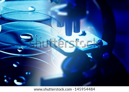 Microscope with biological material in laboratory and petri dish. Blue tone.