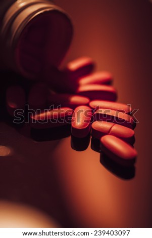 Pills scattered on a glass surface. Dark style.