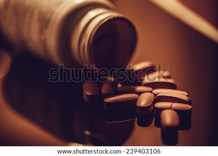 Pills scattered on a glass surface. Dark style.
