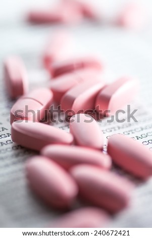 Pills scattered on paper with DNA data. Small depth of field.