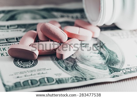 Pills scattered on one hundred dollar bill. Macro image.