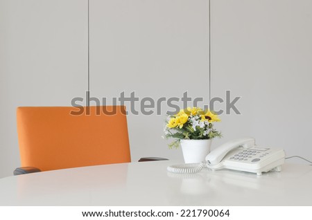 laptop telephone and flower in vase on desk, work space