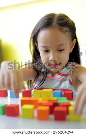 Adorable little girl playing toy blocks in a bright room - copy space on upper-left portion