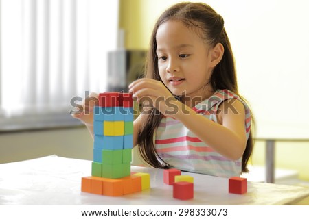 Adorable little girl playing toy blocks in a bright room - copy space on upper-left portion
