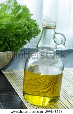 Olive oil bottle placed in kitchen with blur green vegetable in background