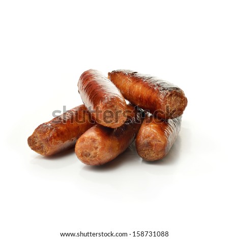 Studio close up of pin sharp focus grilled pork sausages stacked against a white surface with soft shadows. Copy space.