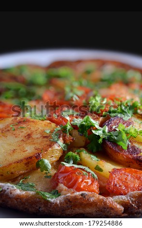 Freshly made traditional Spanish Omelette with sun dried tomatoes against a dark background. From my Pub Food Set. Copy space.