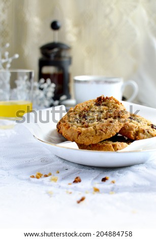 Fresh fruit and oat cookies on a breakfast table with orange juice, white flowers and coffee. Copy space.
