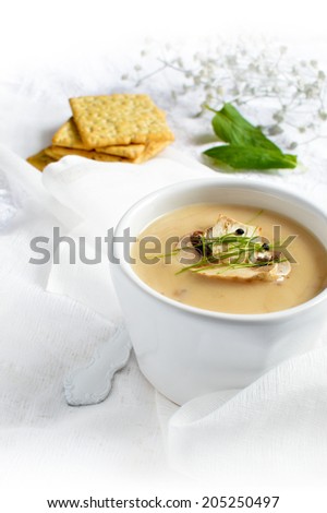 Creamy mushroom soup with garlic chive garnish against a light background. Copy space.