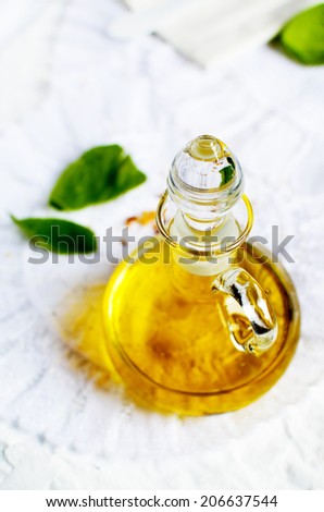 Olive oil in glass decanter with basil against a white background. Copy space.