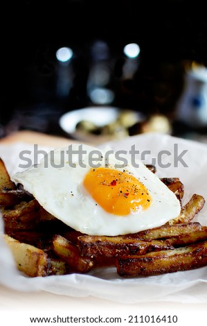 Fried egg, sunny side up, on a bed of roasted chip potatoes seasoned with rock salt and five peppers.