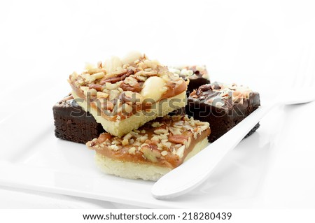 Freshly baked chocolate brownies with brown and white chocolate curls against a white background. Copy space.