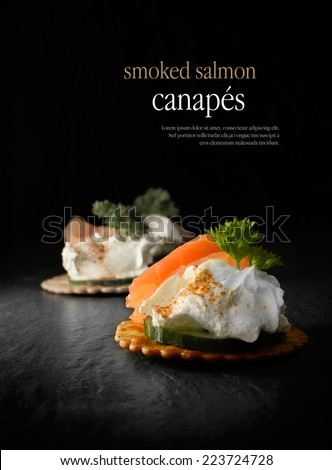 Creatively lit smoked salmon canapes against a black background. Copy space.