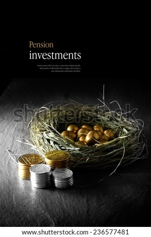 Creatively lit concept image for pension investments. Gold eggs in a grass birds nest with stacked coins against a black background. Copy space.