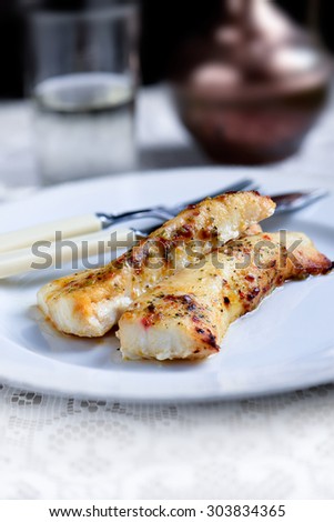 Two fresh grilled cod fillets with ginger, chilli and lime dressing against a rustic background with selective focus and copy space. The perfect image for your fish restaurant lunch menu.