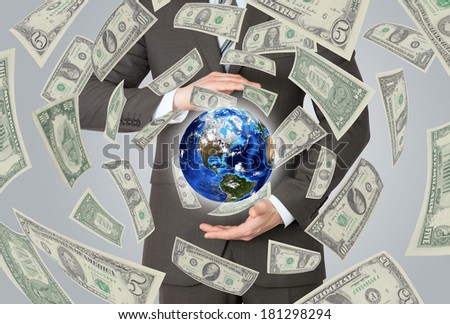 Businessman in a suit holding a earth. Money falling around. Elements of this image furnished by NASA