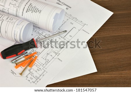 Construction drawings, screwdriver and screws on a wooden surface. Desk builder