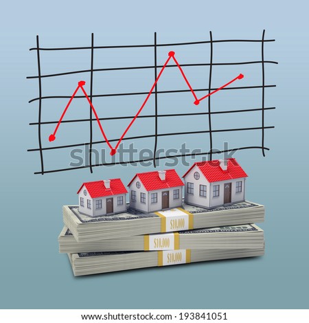 Small houses stand on pack of dollars. Schedule price changes in the background