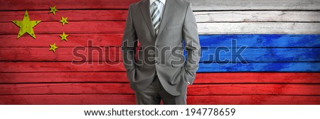 Businessman in a suit. China and Russian flags as background. Concept of business