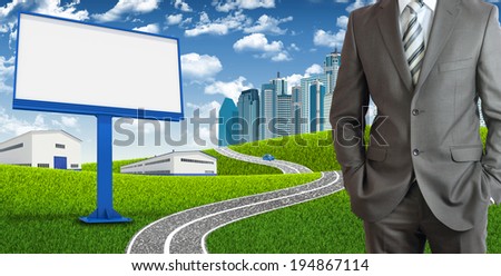 Businessman standing with hands in pockets. Blank billboard, road, skyscrapers and industrial area as backdrop
