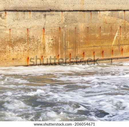 Seawater and the old concrete wall. Water obstacle