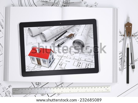 Small house with drawings displayed on tablet screen. Under the tablet lying open book and drawings with tools of architect. Construction concept