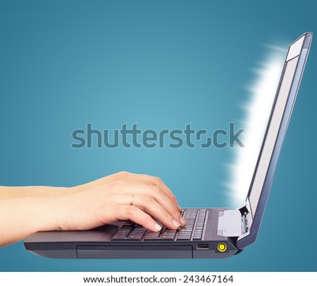 Female hands using laptop, side view, on light blue background
