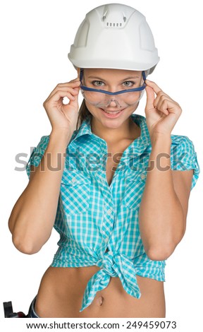 Woman wearing hard hat looking at camera over protective glasses, smiling. Isolated on white background