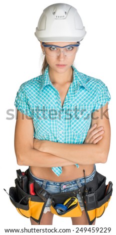 Woman in hard hat, tool belt, adjusting protective glasses with her hands crossed on her breast, looking at camera. Isolated on white background