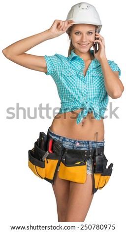 Woman in hard hat and tool belt calling on mobile phone, looking at camera. Isolated on white background