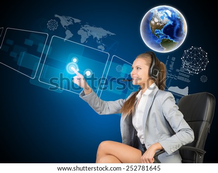 Businesswoman in headset sitting on chair, using touch screen interfaces. Globe above, with blue technology background. Element of this image furnished by NASA