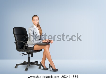 Businesswoman sitting on office chair in empty room, holding laptop