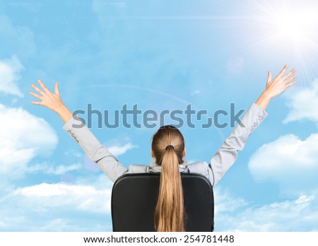 Businesswoman sitting on office chair with her hands outstretched. Sky with clouds as backdrop