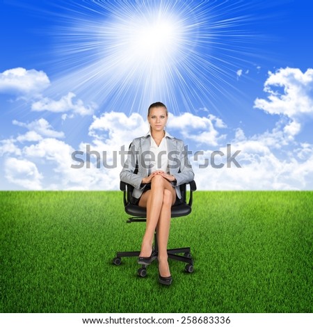 Woman in jacket sits on chair. Background of grass, clouds and sun