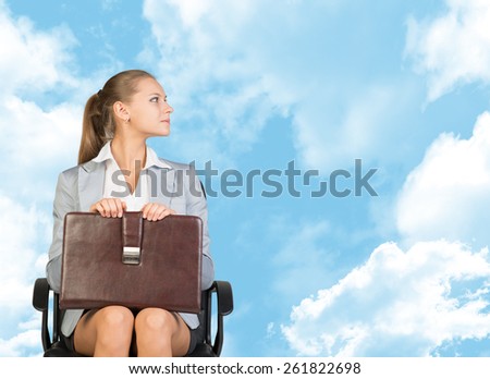 Business woman in skirt, blouse and jacket, sitting on chair. Against background of blue sky and clouds