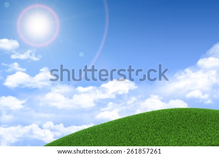 Green grassy hill. Background clouds and bright sun