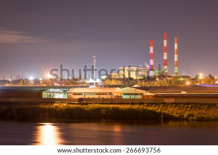 Industrial area with power plant and river port. Behind the houses, in front of river. Night view