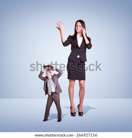 High angry girl talking on phone, small man covered briefcase. Clouds and cement surface as background. Business concept