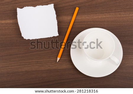 Blank piece of paper with pencil and tea cup on brown wood table