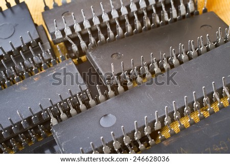 Used black electronic computer chips made of plastic with silver metallic legs arranged in rows upside-down, close-up