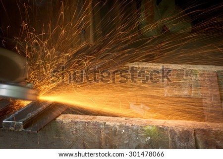 Grinding of steel sheets with electrical grinder. Long lines of flying hot sparkles deflected by some obstacles