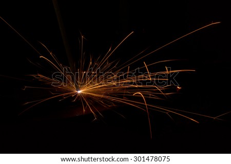 Welding of steel sheets with electrical arc. Long lines of flying hot sparkles and blinding arc discharge.