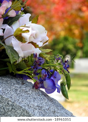 silk flowers on a cemetery grave headstone