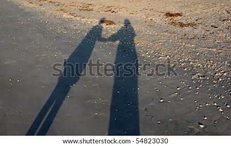 stock photo : shadows two people holding hands morning sun beach