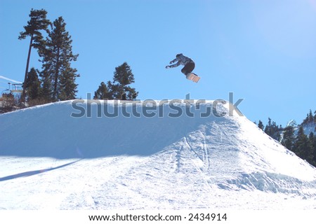 Snowboarder going off of a big jump.