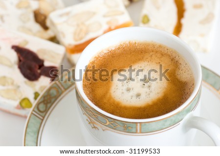 Breakfast composition with cup of fresh coffee and slices of nougat. Selective focus.