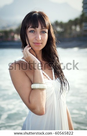 Attractive brunette model standing in water in wet white dress. Southern Tenerife, Canary Islands.