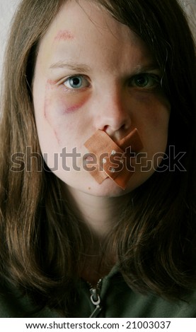 A young woman with a wound on her cheek and a plaster on her mouth. A victim of domestic violence keeping silent?