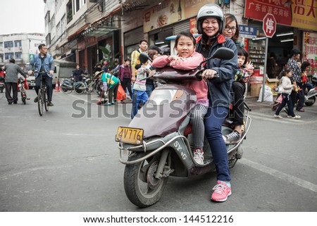 FOSHAN, GUANGDONG/CHINA - MARCH 16: Four unidentified people share the same scooter. Shunde District of Foshan City, Guangdong Province in Southern China on March 16th, 2013.