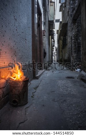 Chinese coal stove burning in a back alley in Shunde District of Foshan City, Guangdong Province in Southern China.